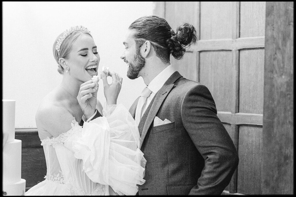 Bride and groom cake moment with The Iced Vegan Wedding Cakes. Layer Marney Town. Models Samuel and Grace. Veni Infantino. Tracey Davies Photography. 